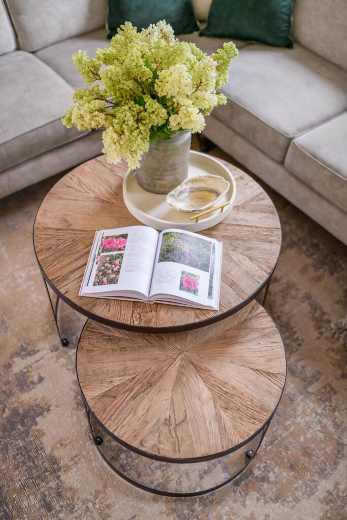 Round wooden coffee table styled with fresh flowers and an open book – Cloyne Farmhouse Part One project, designed by AK Interior, Cork, Ireland.