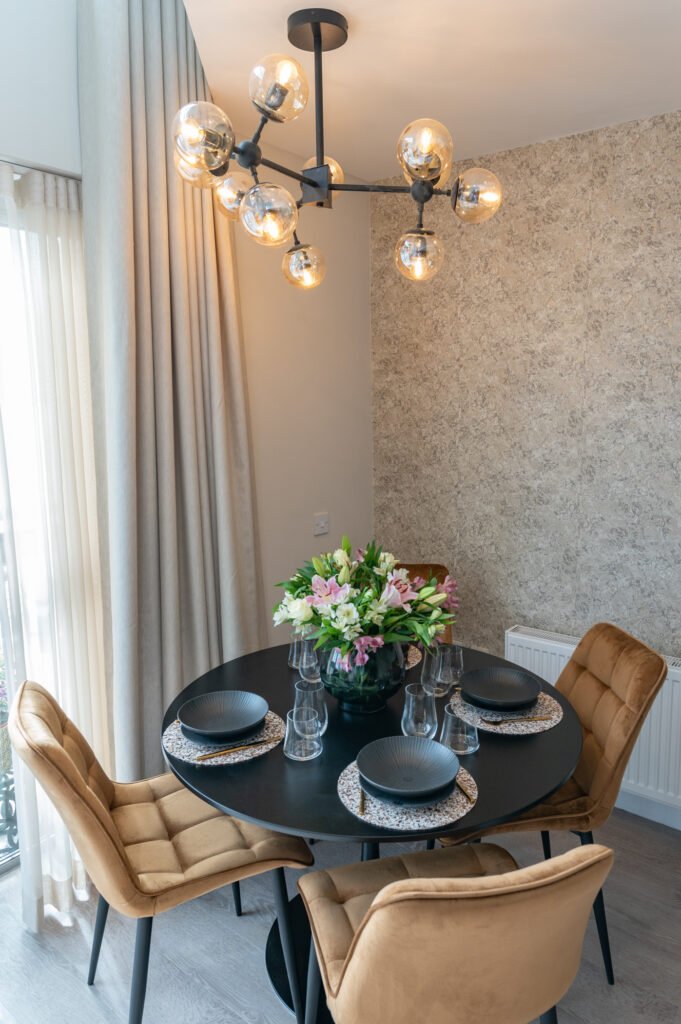 Dining area with a black round table, four brown chairs and a flower arrangement. West Cork Waterfront project by AK Interior, Cork, Ireland.