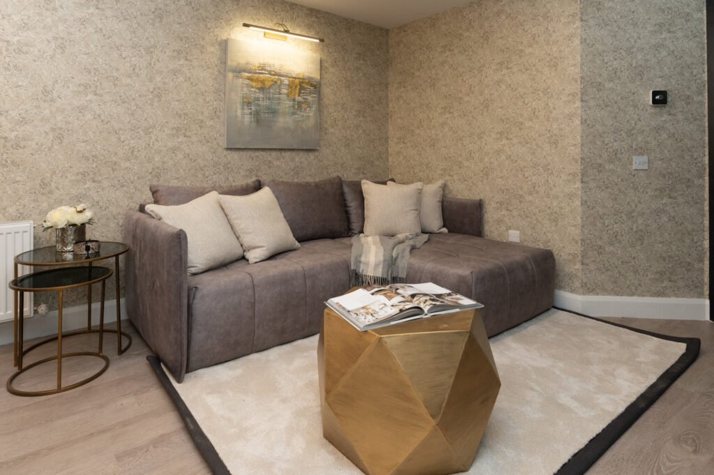 Grey sofa with decorative cushions and a gold geometric coffee table on a rug. West Cork Waterfront project by AK Interior, Cork, Ireland.