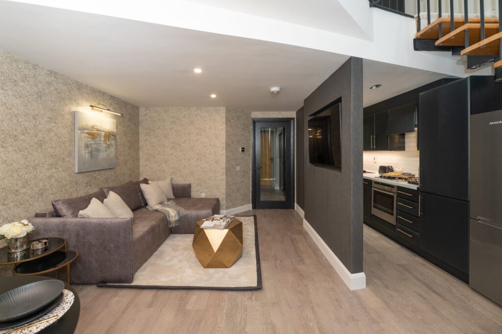 Living room with grey sofa, gold coffee table and door to another room. West Cork Waterfront project by AK Interior, Cork, Ireland.