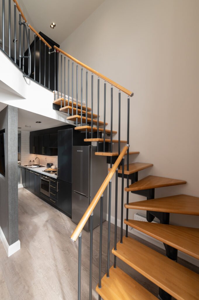 Wooden staircase with black railing next to the kitchen. West Cork Waterfront project by AK Interior, Cork, Ireland.