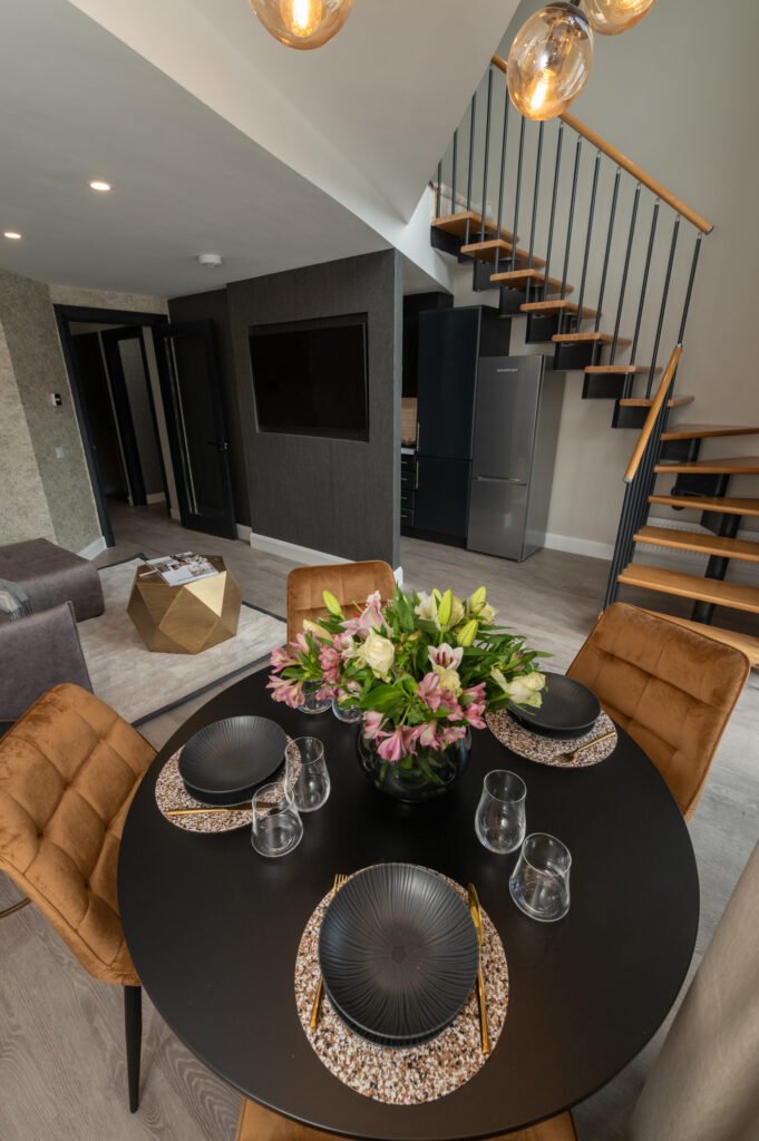 Round table with four brown chairs and a floral arrangement. West Cork Waterfront project by AK Interior, Cork, Ireland.