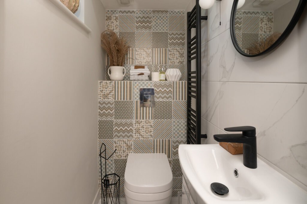 Small bathroom with toilet, white sink and patterned wall tiles. West Cork Waterfront project by AK Interior, Cork, Ireland.