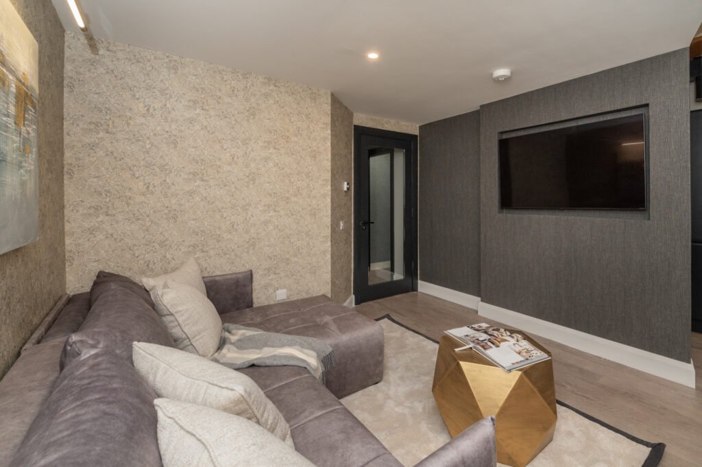 Living room with grey sofa, gold table and dark TV wall. West Cork Waterfront project by AK Interior, Cork, Ireland.