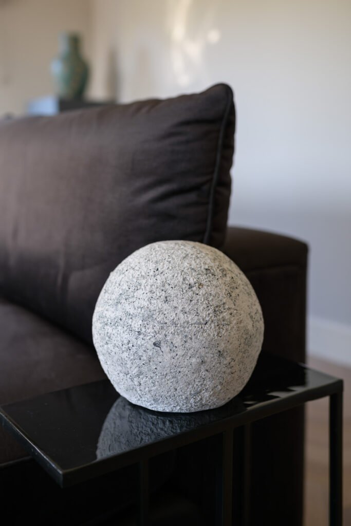 Grey stone ball sculpture on black side table beside deep brown sofa, Rathmore Residential project, AK Interior, Cork.