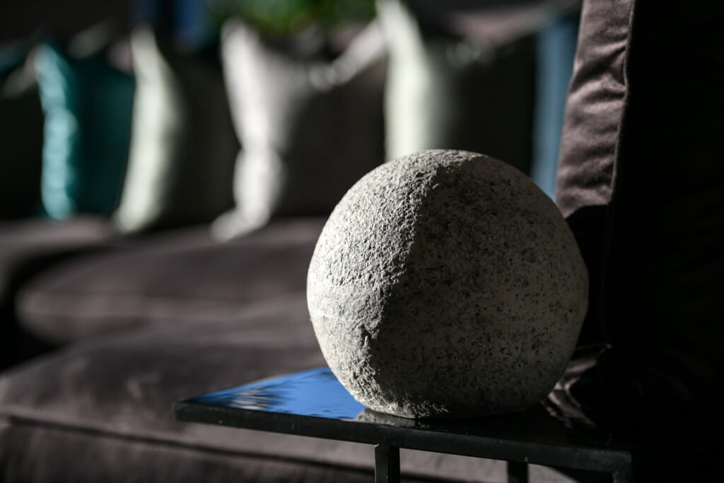 Close-up of stone sphere ornament with blurred teal cushions in the background, Rathmore Residential project, AK Interior, Cork.