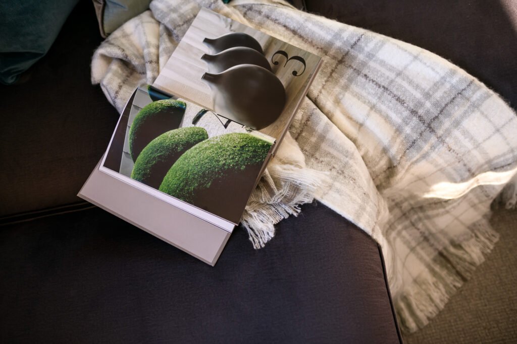 Sofa arm with plaid throw, art book and green sculptural objects, Rathmore Residential project, AK Interior, Cork.