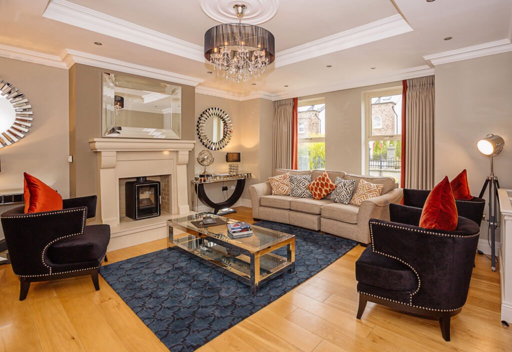 Classic living room with fireplace, cream sofa and black armchairs with orange cushions. Rockport Residential project, AK interior.