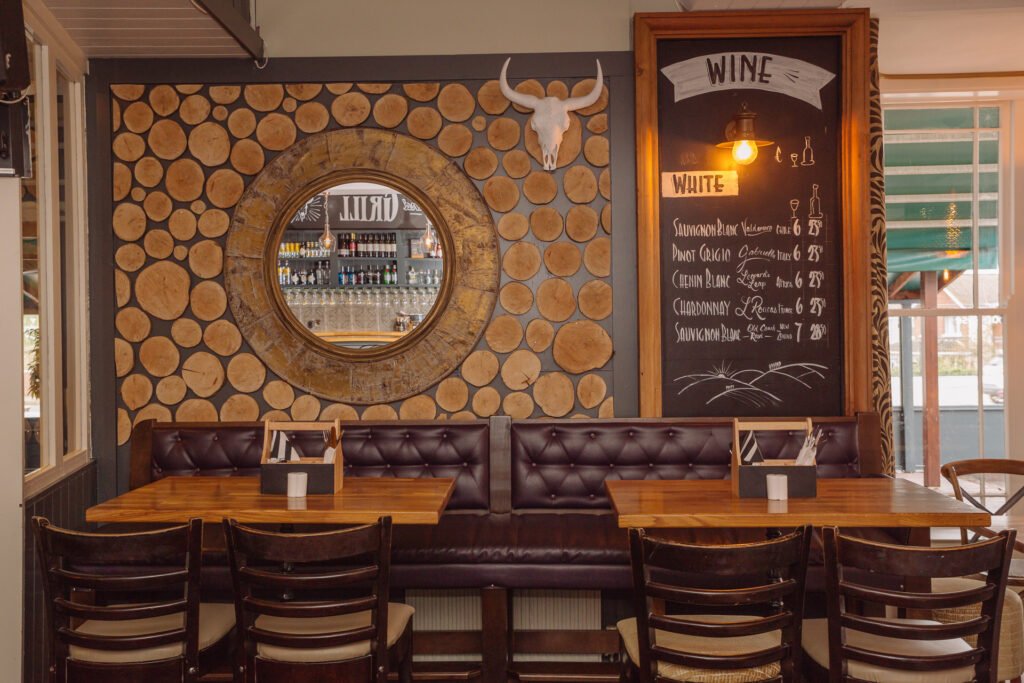 Cosy dining area with timber chairs, patterned wallpaper and warm wall lights. Briar Rose Commercial project, AK Interior, Cork.