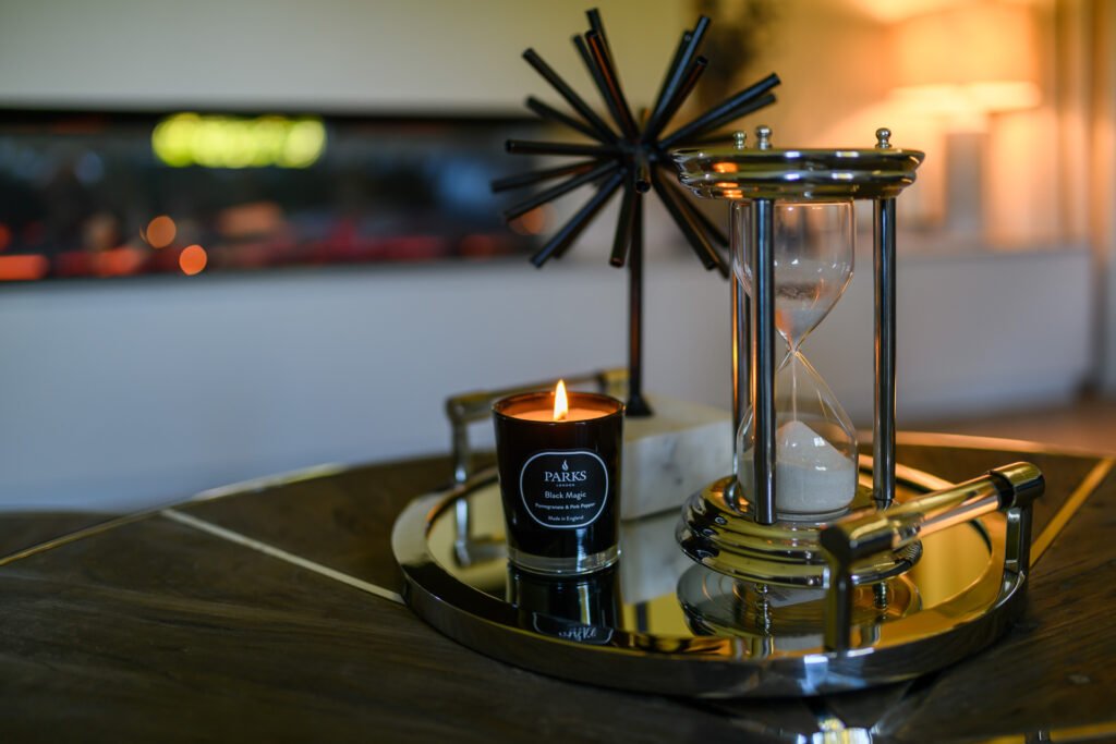 Night-time vignette with candle, hourglass and black starburst sculpture on round table, Rathmore Residential project, AK Interior, Cork.