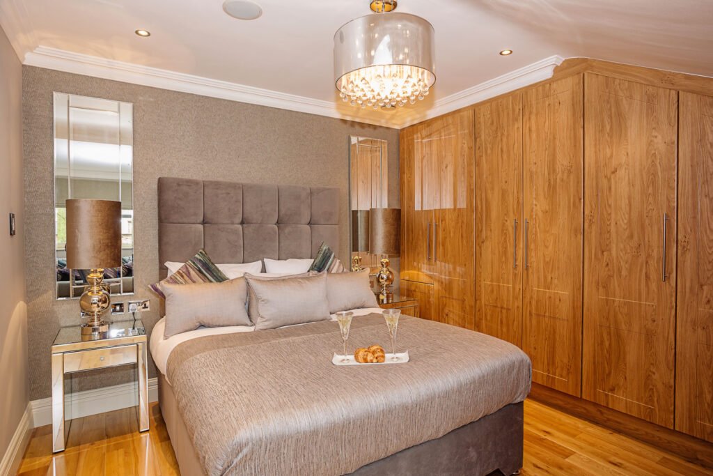 Master bedroom with upholstered headboard, chandelier and seating by large windows. Rockport Residential project, AK Interior, Cork.