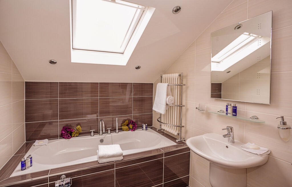 Contemporary bathroom with large built-in bathtub under skylight and white basin. Rockport Residential project, AK Interior, Cork.
