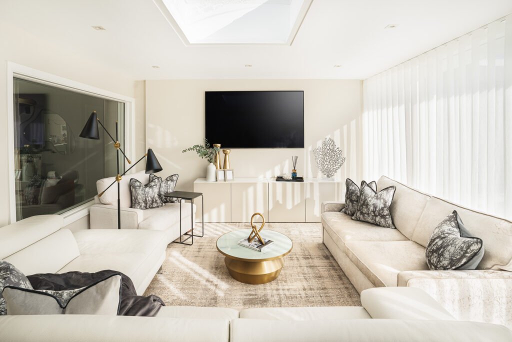 Spacious living room with central coffee table, neutral rug and wall-mounted TV – Moneygurney Road Part One by AK Interior.