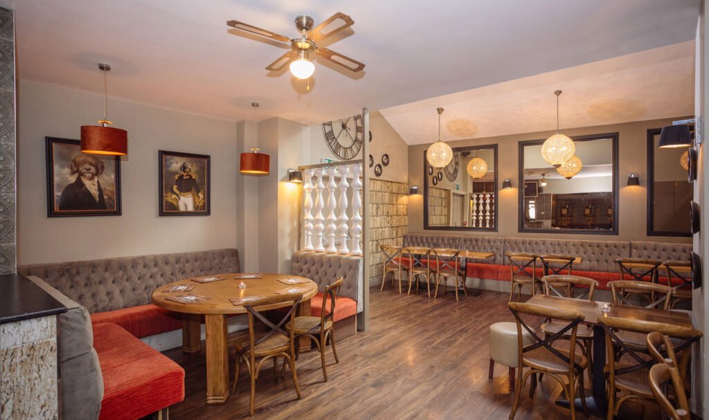 Dining area with long banquette seat, framed artwork and warm pendant lights. Briar Rose Commercial project, AK Interior, Cork.