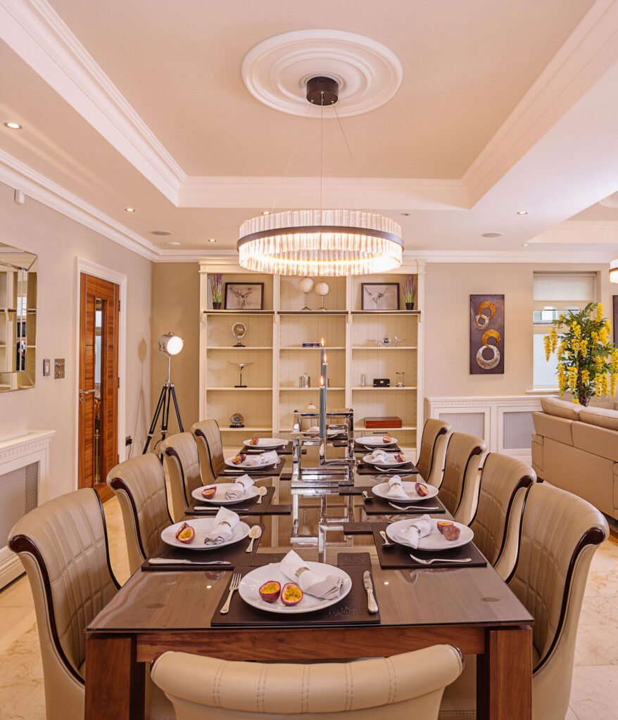 Formal dining room with long wooden table, cream leather chairs and crystal chandelier. Rockport Residential project, AK interior.