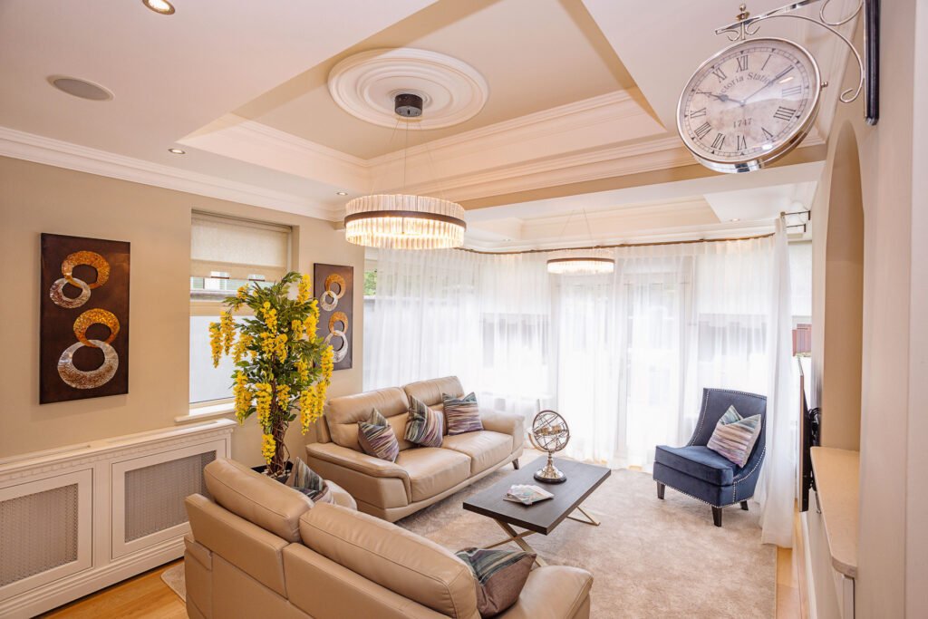 Elegant open-plan lounge with cream sofas, large clock and decorative ceiling detail. Rockport Residential project, AK interior.