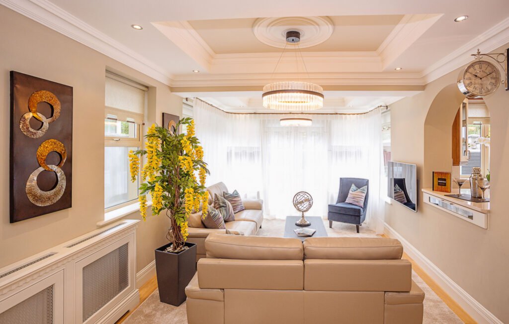 Cosy living room with cream sofas, patterned cushions and navy accent chair facing the garden. Rockport Residential project, AK interior.