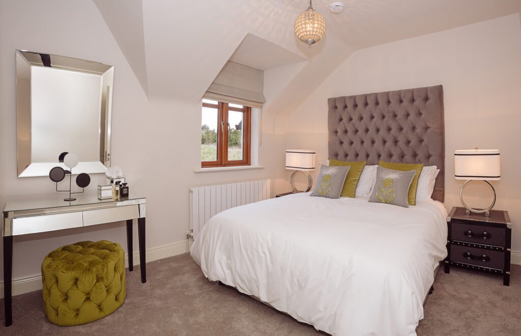 Bright bedroom with tufted grey headboard, bedside lamps and white bedding – Innishannon Showhouse by AK Interior, Cork Ireland.