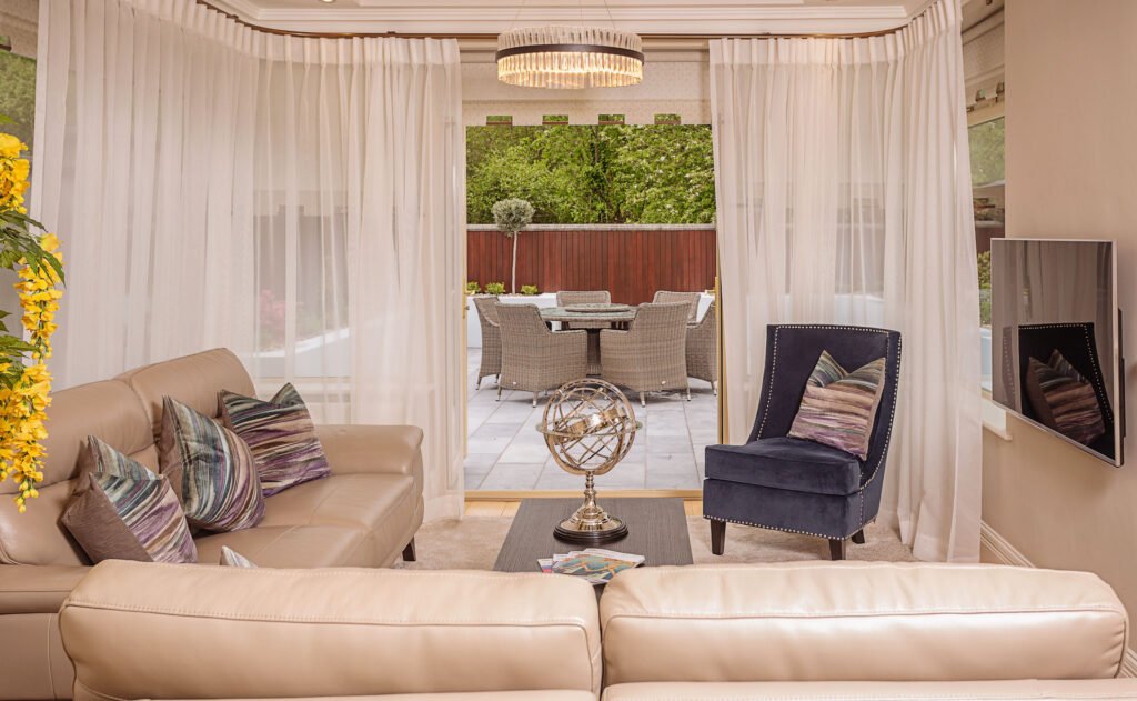 Bright living room with cream leather sofas, sheer curtains and view to the outdoor dining terrace. Rockport Residential project, AK interior.