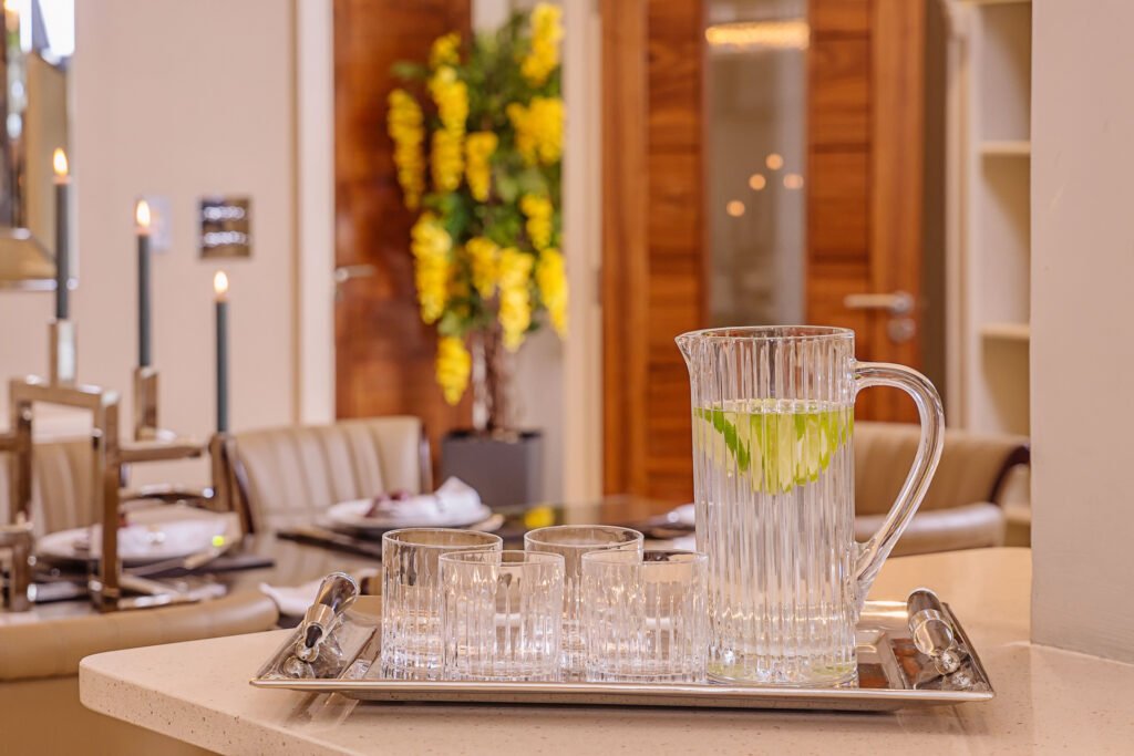 Close-up of ribbed glass jug with lime water and matching tumblers on a silver tray. Rockport Residential project, AK interior.