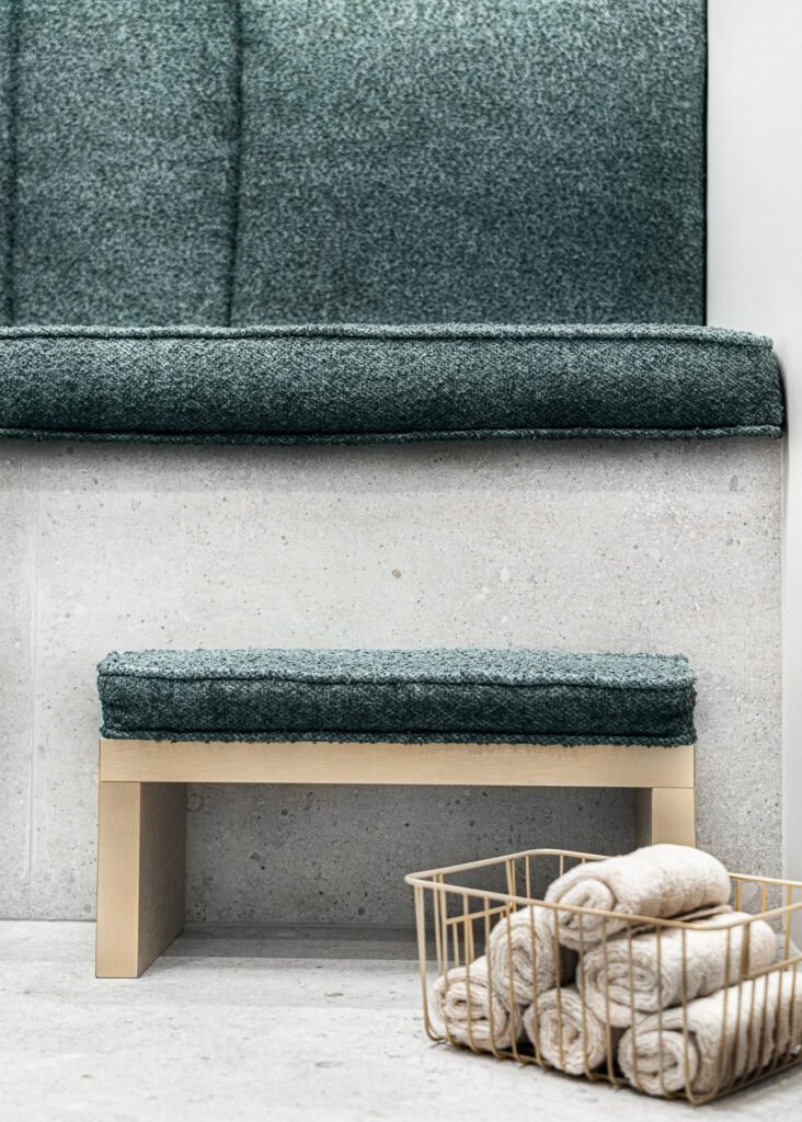 Green textured bench with rolled towels in a gold basket on concrete steps – Bon Me project, designed by AK Interior Cork.