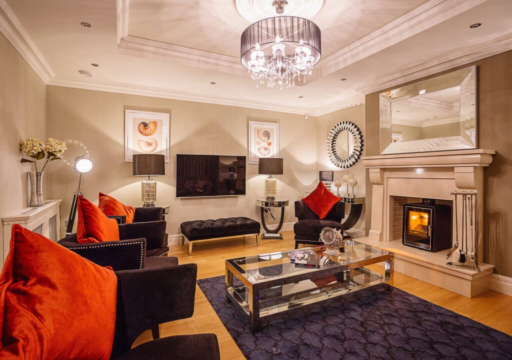 Evening living room scene with lit fireplace, deep blue rug and orange accent cushions. Rockport Residential project, AK interior.