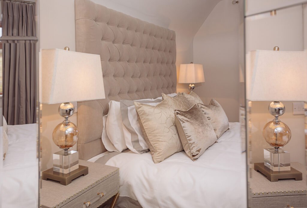 Close-up of tufted headboard with satin decorative pillows and glass bedside lamps – Innishannon Showhouse by AK Interior, Cork Ireland.