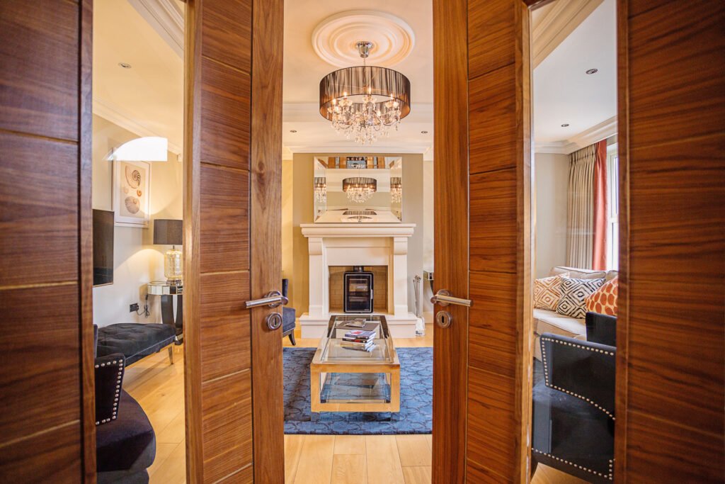 View through wooden double doors into living room with fireplace and blue rug. Rockport Residential project, AK interior.