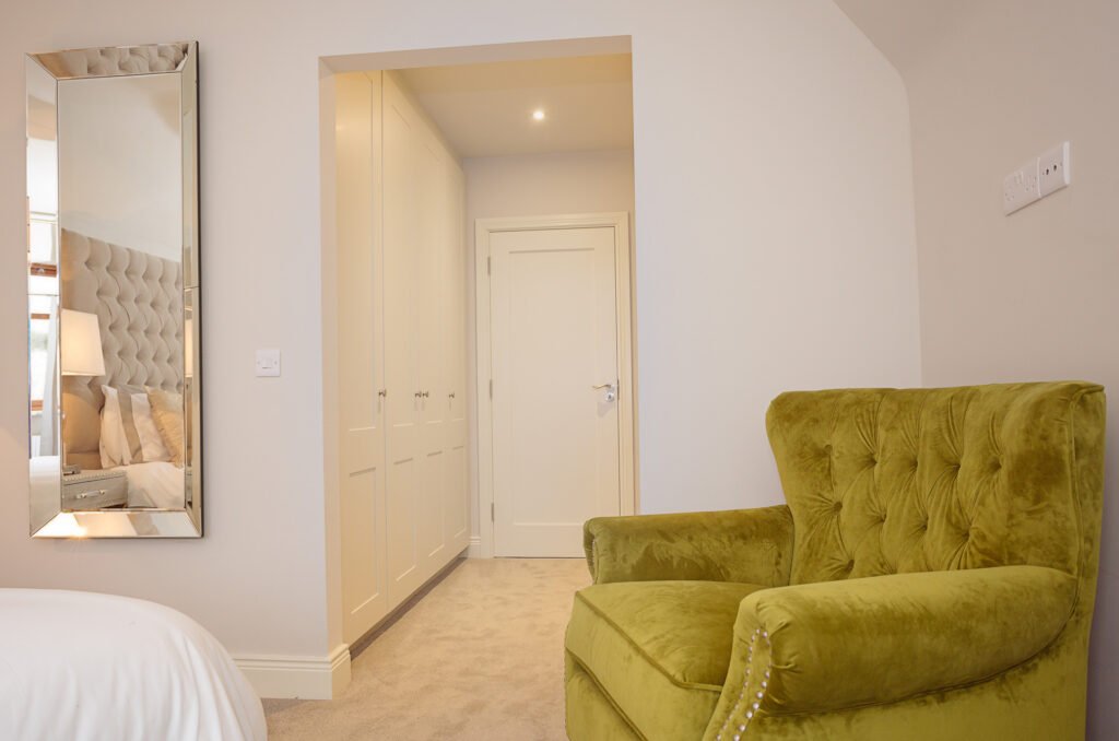 Bedroom nook featuring built-in wardrobes and green velvet accent chair – Innishannon Showhouse by AK Interior, Cork Ireland.