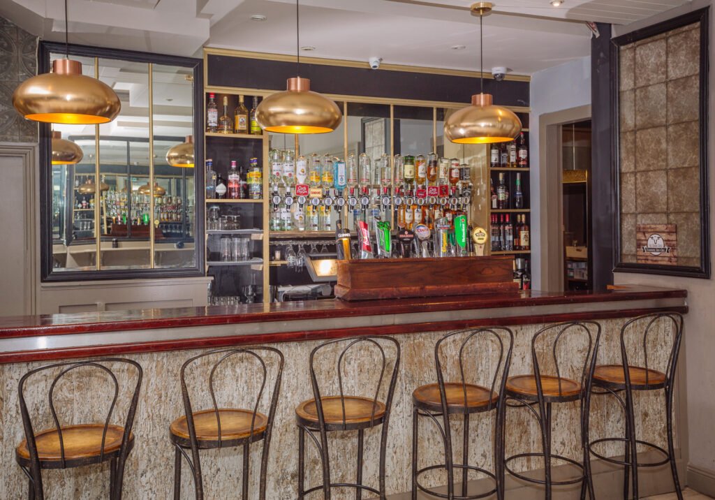 Bar area with brass pendant lights, mirrored back bar and high stools. Briar Rose Commercial project, AK Interior, Cork.
