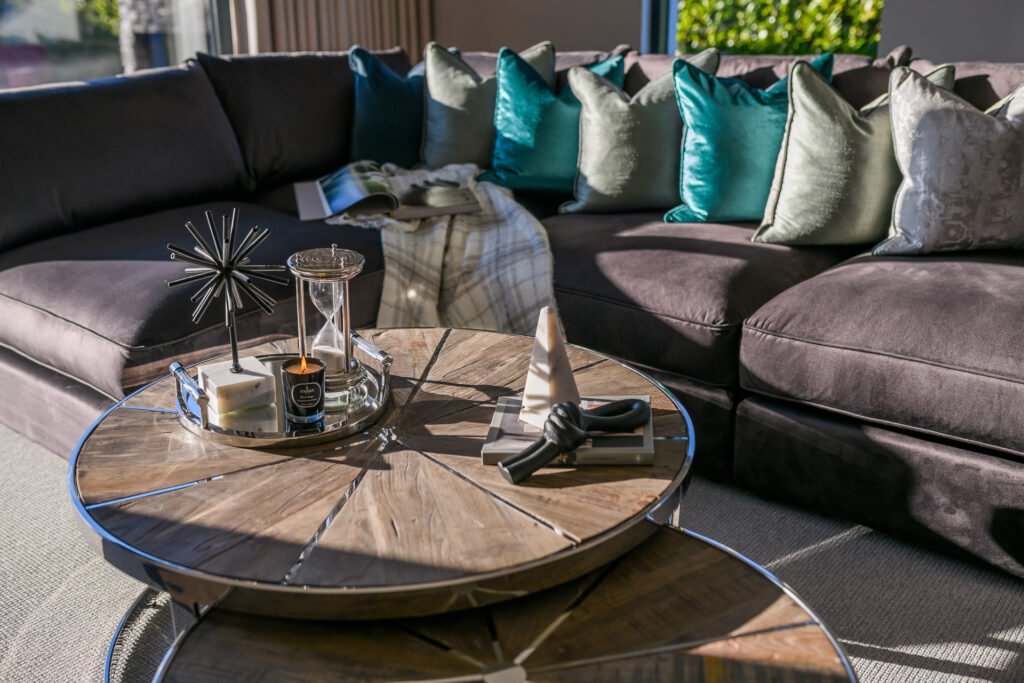 Close-up of purple sectional sofa with teal and silver cushions and styled wooden coffee table, Rathmore Residential project, AK Interior, Cork.
