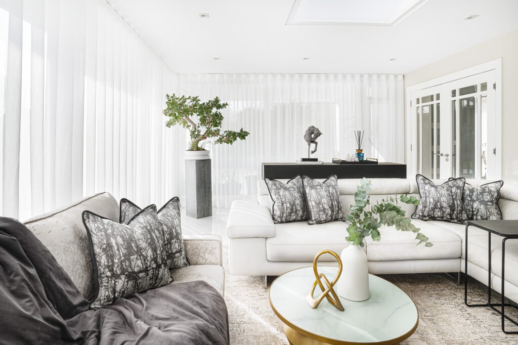 Modern living area with large windows, bonsai decor and light minimalist sofas – Moneygurney Road Part One by AK Interior.