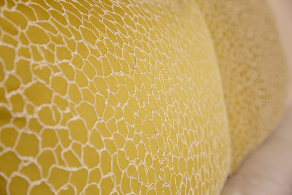 Close-up of yellow textured decorative pillow on bed – Innishannon Showhouse by AK Interior, Cork Ireland.