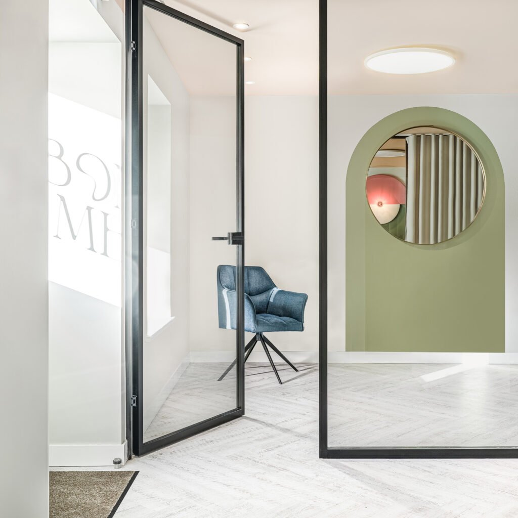 Glass door entrance with a green arched feature wall and blue chair – Bon Me project, designed by AK Interior Cork.