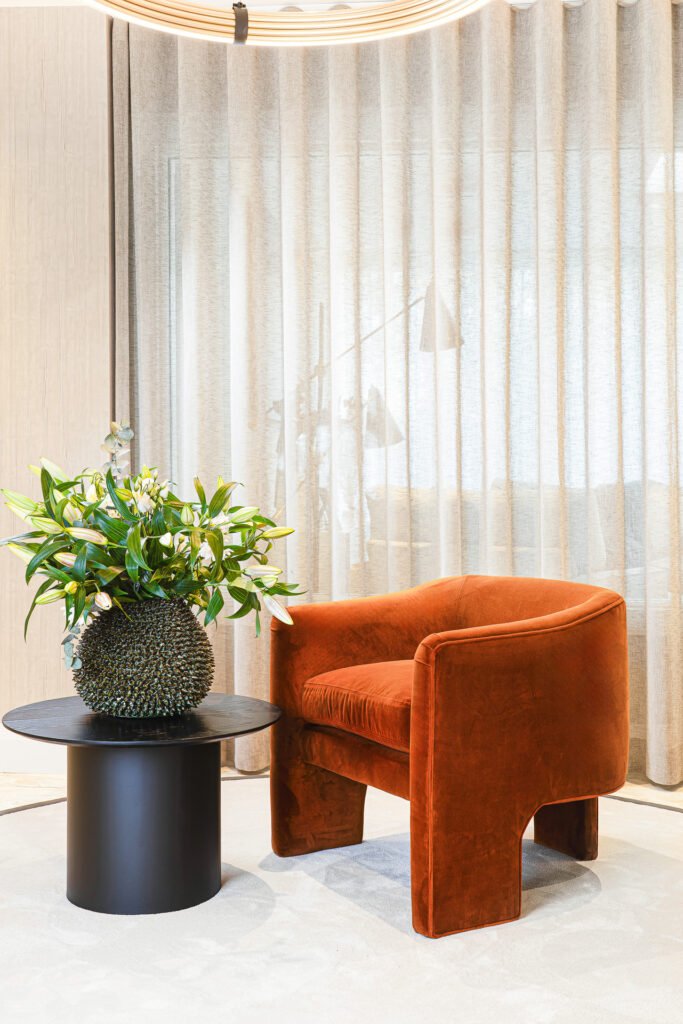 Black planter paired with orange accent chair – Luxury Living Room Part Two by AK Interior.