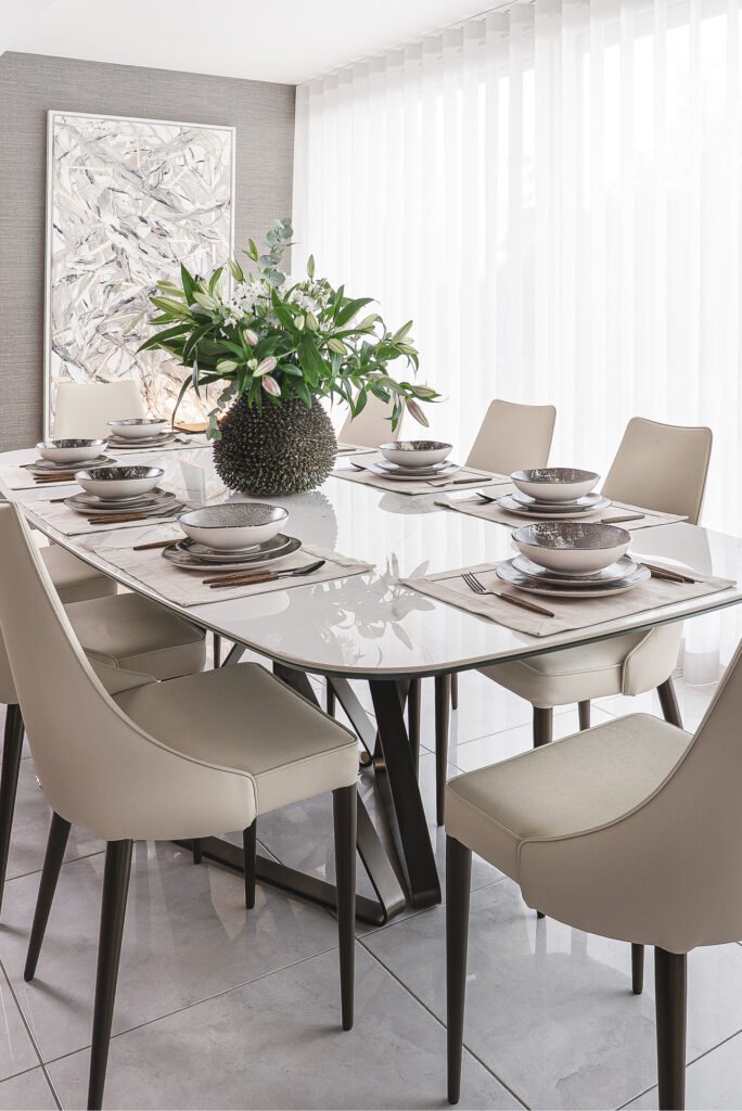 Dining room with statement artwork and contemporary table setting – Luxury Living Room Part Two by AK Interior.