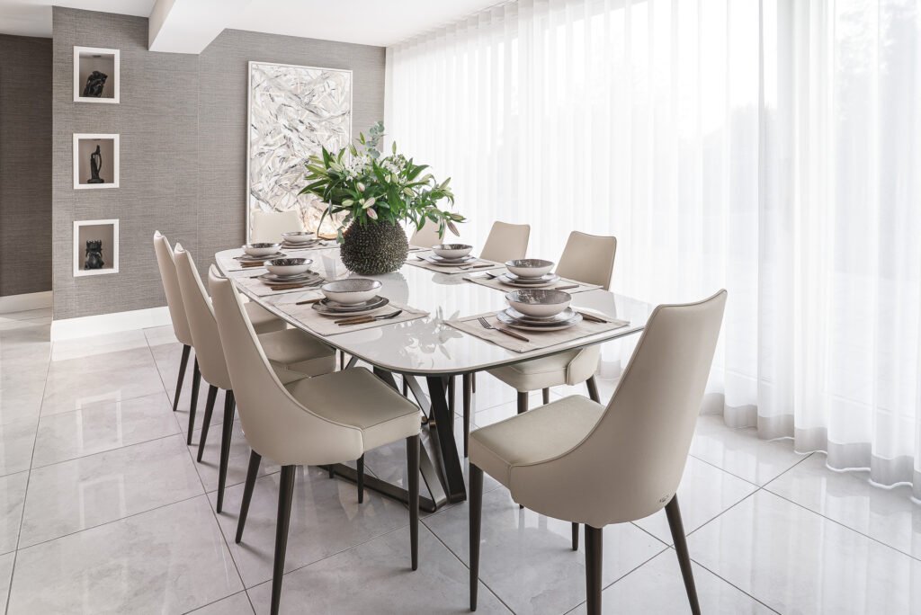Modern dining table with beige chairs and green floral centerpiece – Luxury Living Room Part Two by AK Interior.
