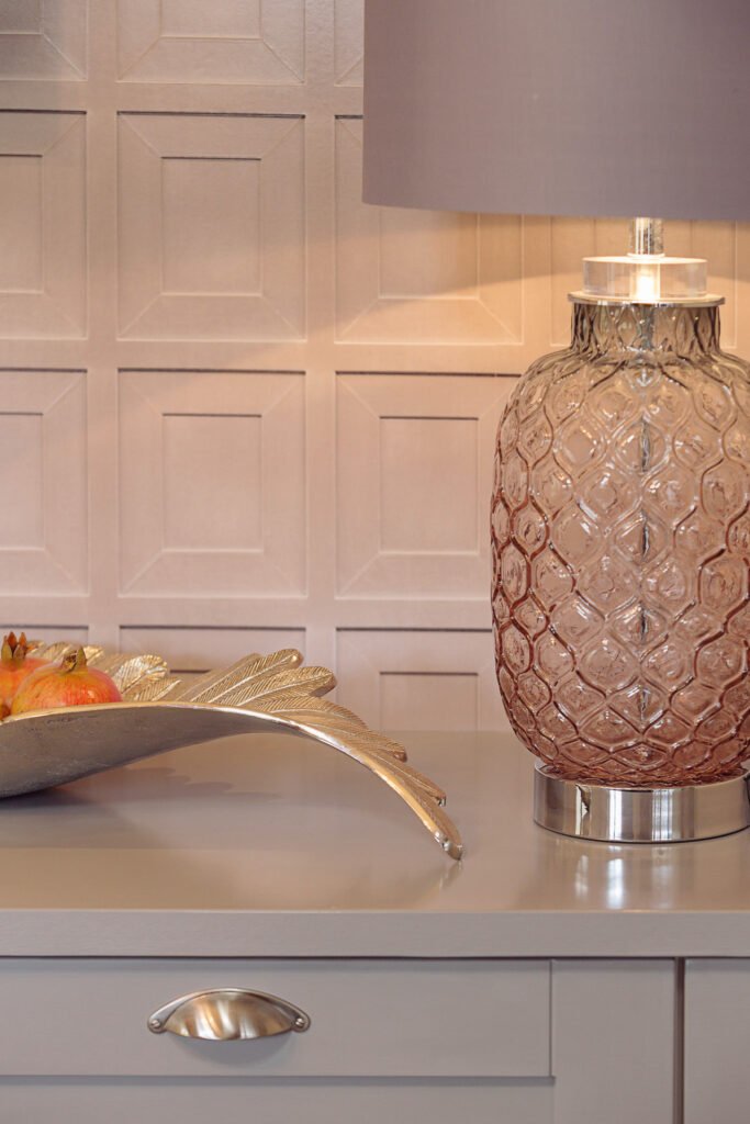 Pink textured glass table lamp with metallic leaf tray and fruit on cabinetry against panelled wall – Innishannon Showhouse by AK Interior, Cork Ireland.