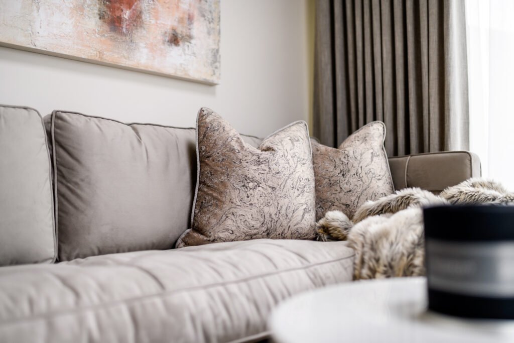Sofa with decorative cushions and grey curtains in the background – Whitegate Holiday Home, AK Interior, Cork