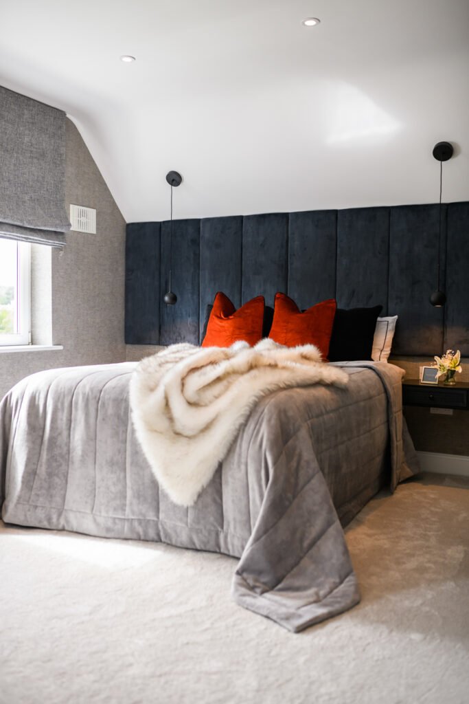 Luxury master bedroom with navy upholstered headboard, orange accent cushions and faux fur throw on grey bedspread, AK Interior Design, Cork, Ireland