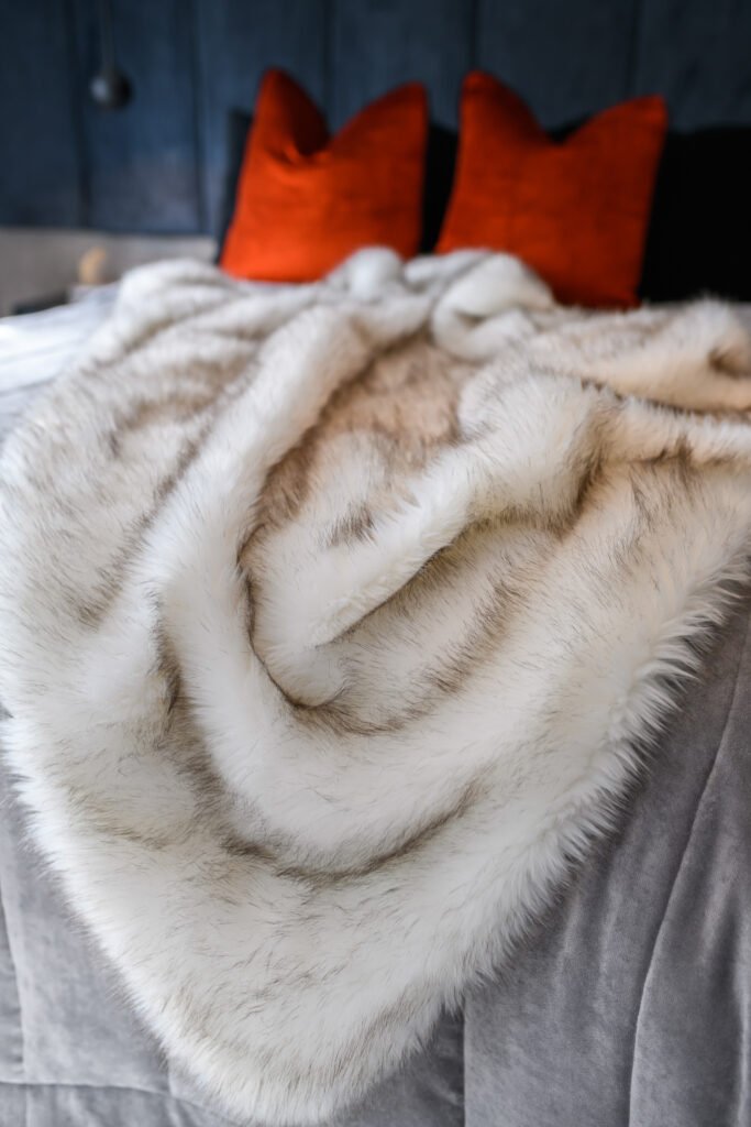 Close-up of soft white faux fur throw layered over grey quilted bedding on a modern bed, AK Interior Design, Cork, Ireland