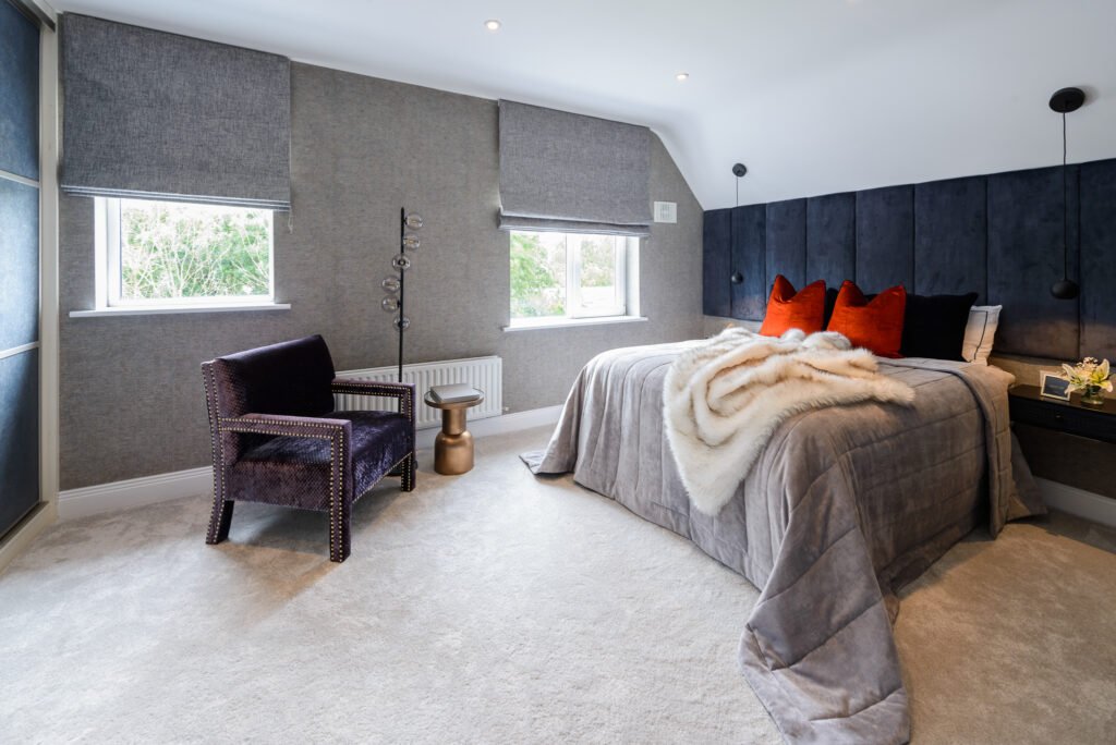 Wide view of contemporary bedroom with statement bed, textured grey walls, accent chair and soft carpet flooring, AK Interior Design, Cork, Ireland