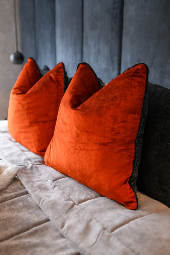 Burnt orange velvet accent cushions on a grey upholstered bed with deep blue velvet headboard, AK Interior Design, Cork, Ireland