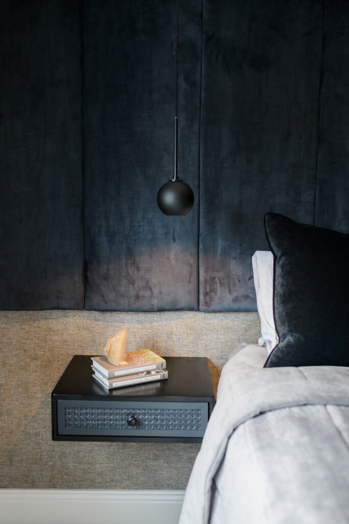 Black pendant bedside light over floating dark bedside table with books and crystal decor in a contemporary bedroom, AK Interior Design, Cork, Ireland