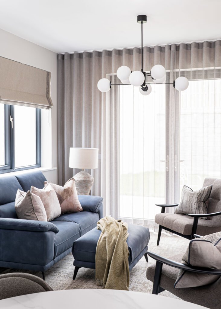 Blue living room sofa styled with neutral cushions near large window – Residential project “The Steeples Part One”, designed by AK Interior, Cork, Ireland.