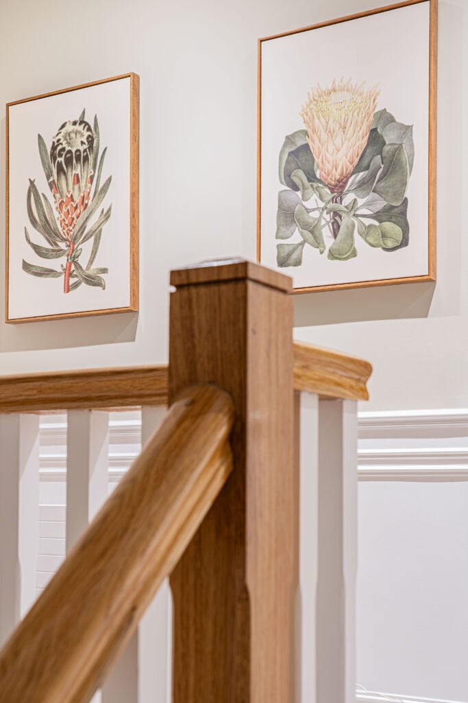 Modern gallery wall display above wooden staircase — The Steeples Part One by AK Interior