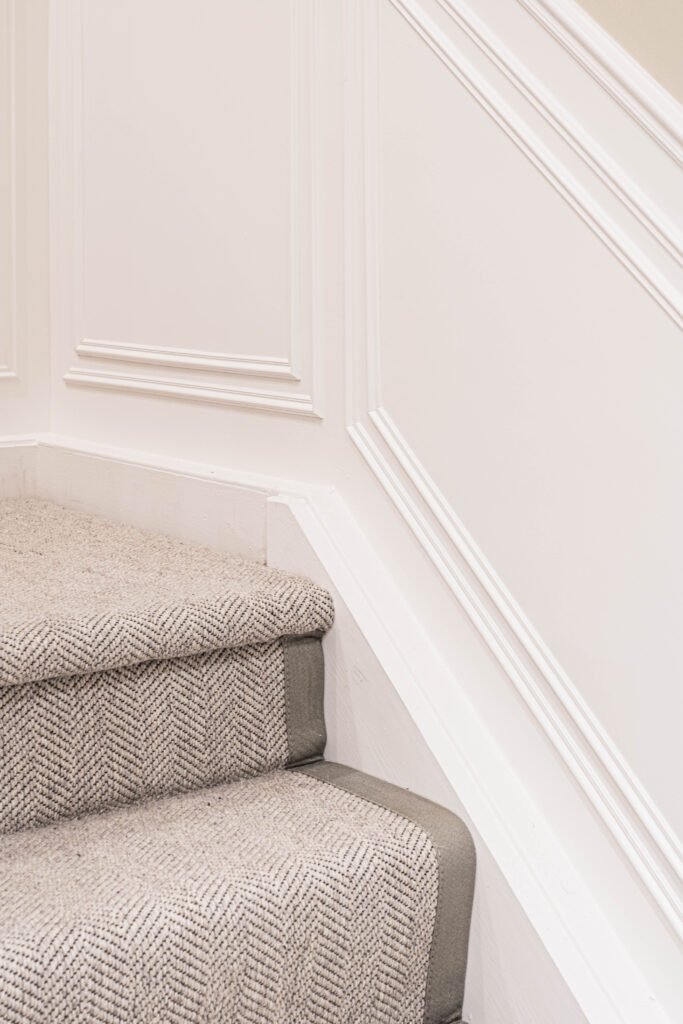 Curved staircase corner with white panelling and plush carpeting — The Steeples Part One by AK Interior