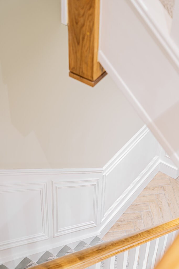 Staircase detail with white spindles and warm wood accents — The Steeples Part One by AK Interior