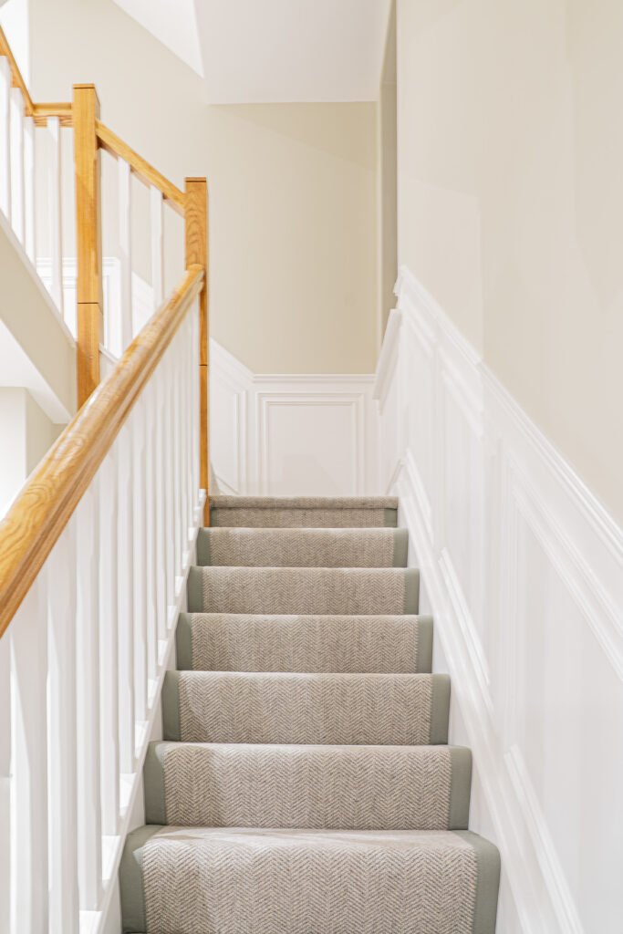 Bright hallway interior with carpeted staircase and white panelled walls — The Steeples Part One by AK Interior