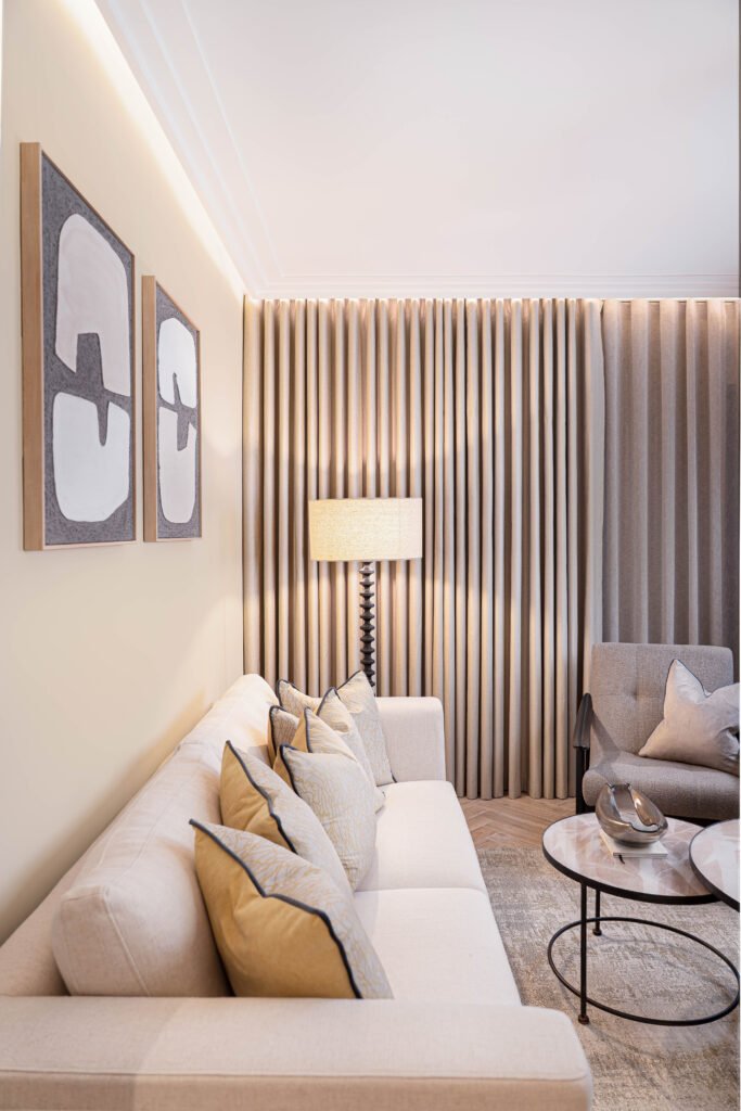 Neutral living room corner with abstract framed artwork and soft lighting — The Steeples Part One by AK Interior